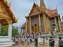 A Thai temple complex with several ornate buildings, and a lot of visitors